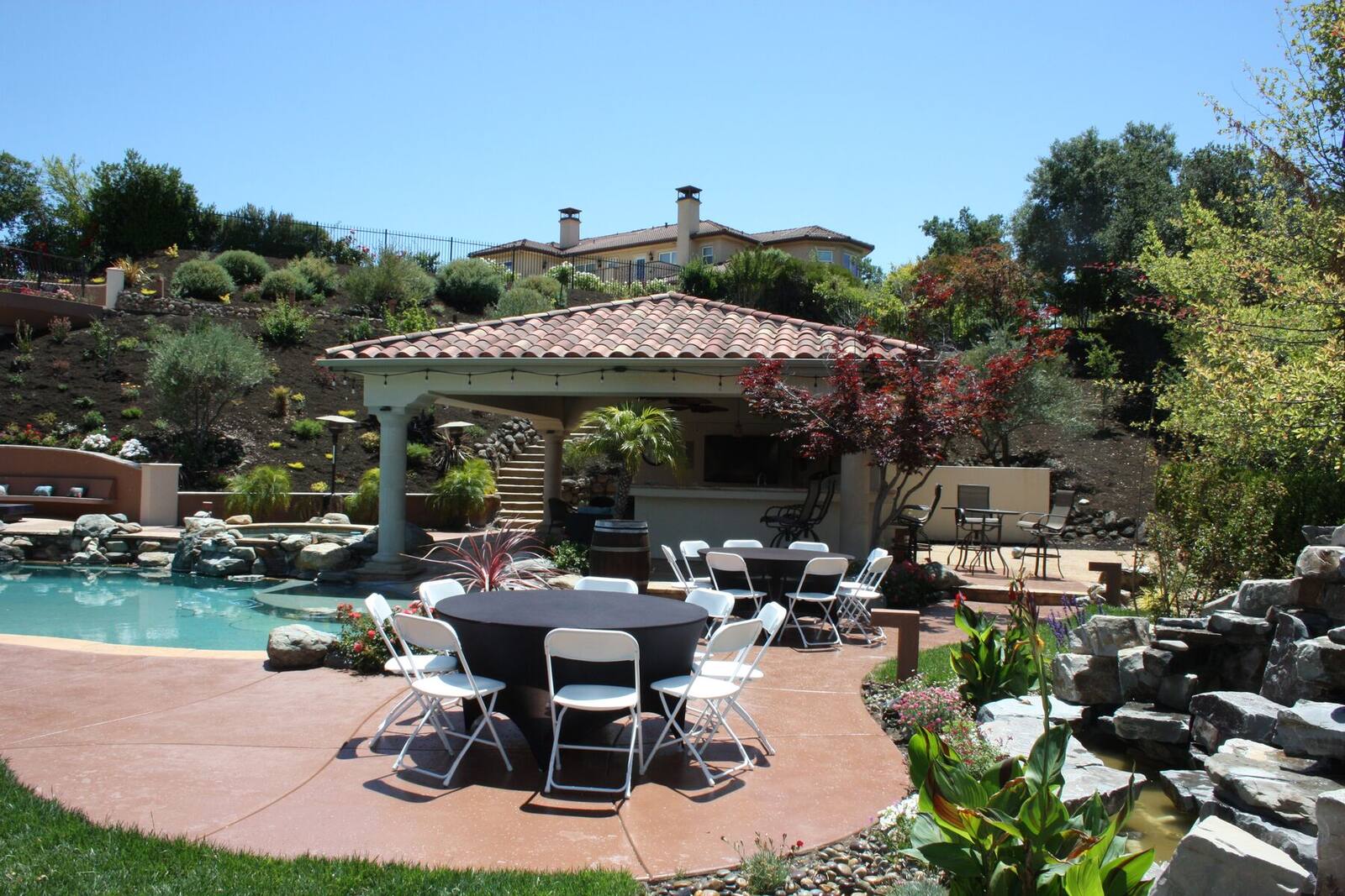 The completed lower grounds, pool, lanai, and hillside garden in daylight.