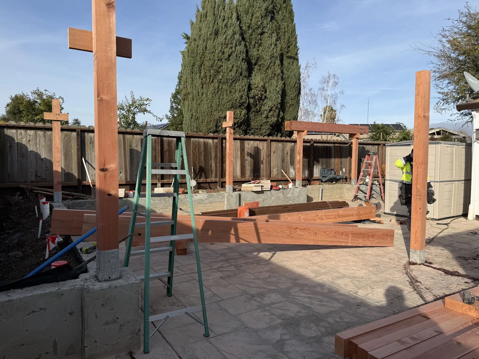 A sequence of timber posts rising from structural bases in the Hernandez backyard.