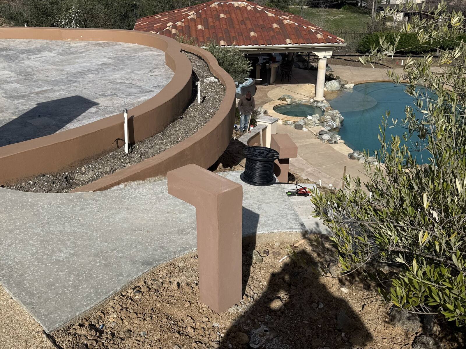 Path grading, lighting posts, and planting installed along the hillside walk.