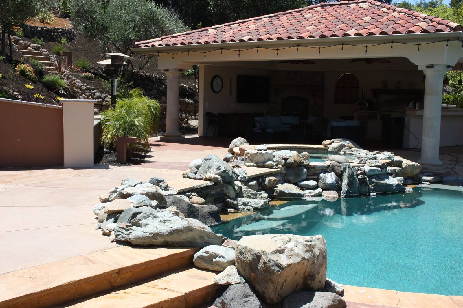 The finished pool and waterfall grotto beside the outdoor living pavilion.