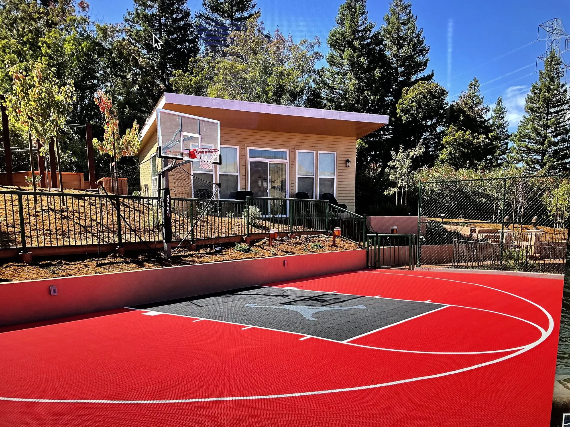 A red sport court with a basketball hoop and an accessory dwelling unit at the upper edge of the property.
