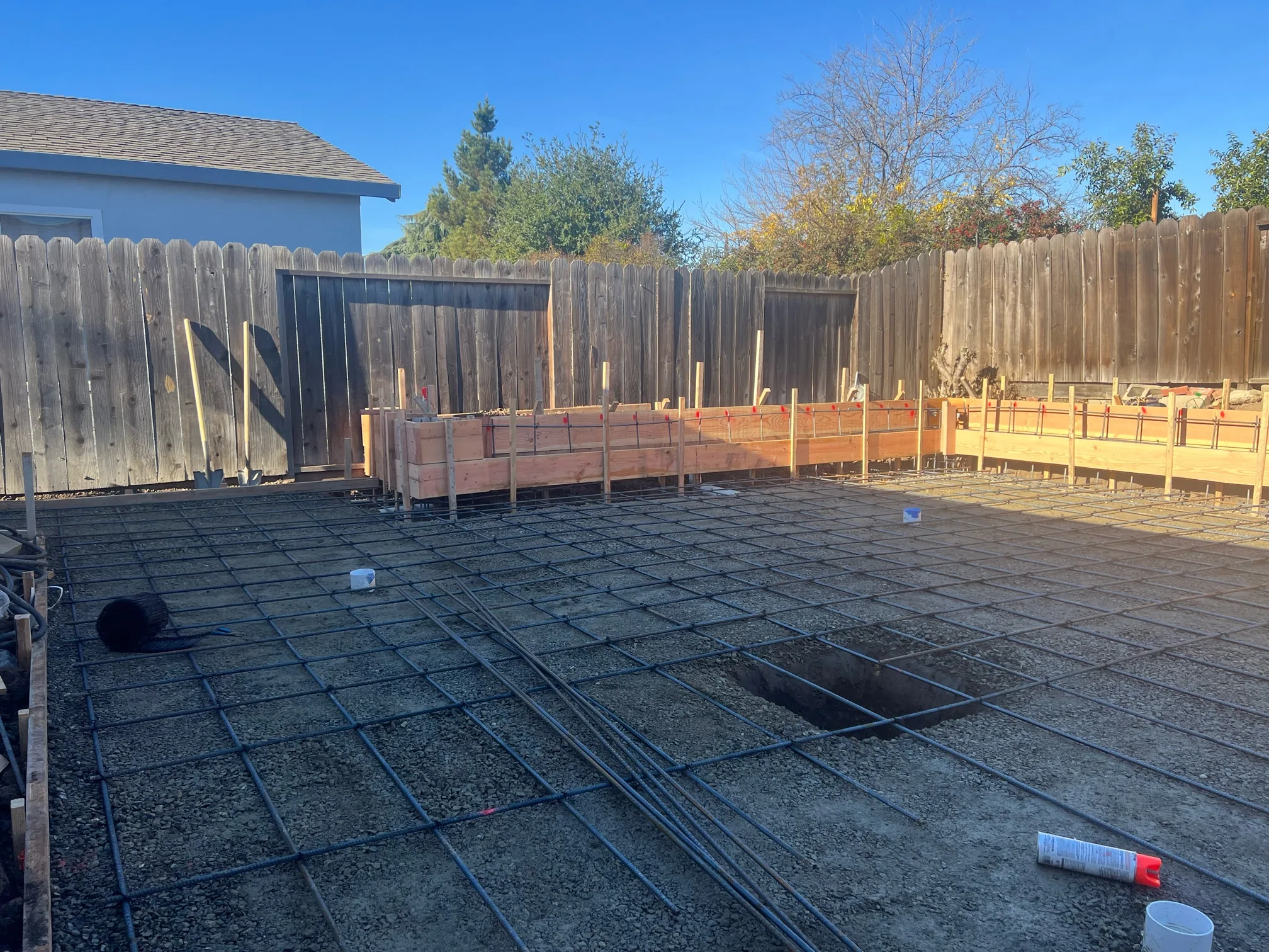 A reinforced steel grid and timber retaining-wall forms laid across the prepared Hernandez backyard.